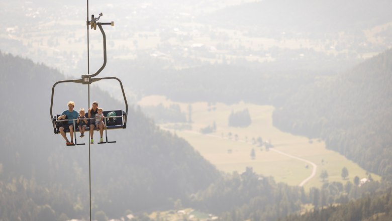 Unterwegs auf den Fadensattel, © NB/Frühmann Eltern sitzen mit ihrem kleinen Sohn und ihrer kleinen Tochter in der Schneeberg Sesselbahn