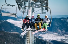 4 Personen sitzen in der Schneeberg Sesselbahn in Wintersportausr&uuml;stung