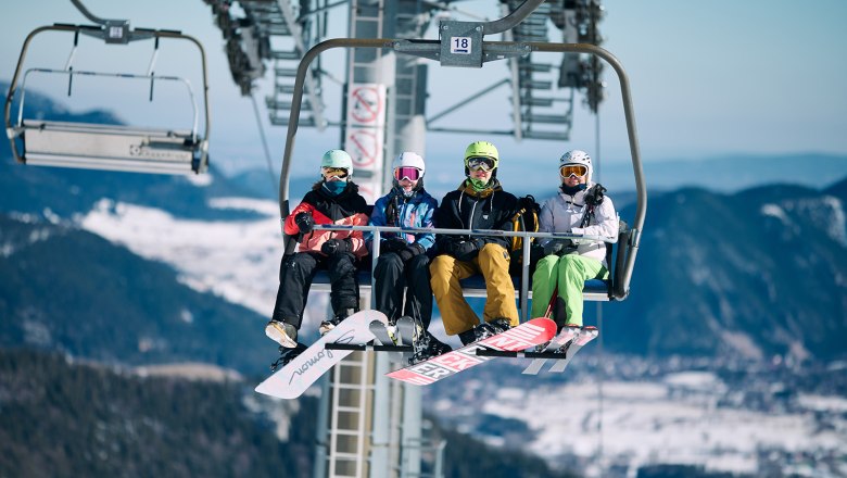 4 Personen sitzen in der Schneeberg Sesselbahn in Wintersportausr&uuml;stung